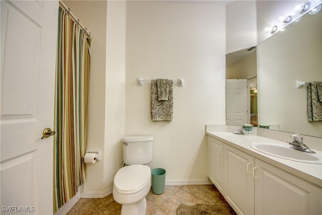 bathroom with baseboards, a sink, toilet, and double vanity