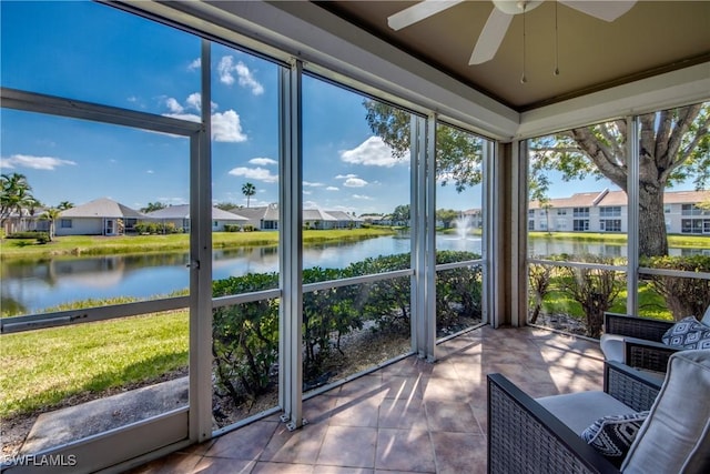 unfurnished sunroom featuring a ceiling fan, a residential view, and a water view