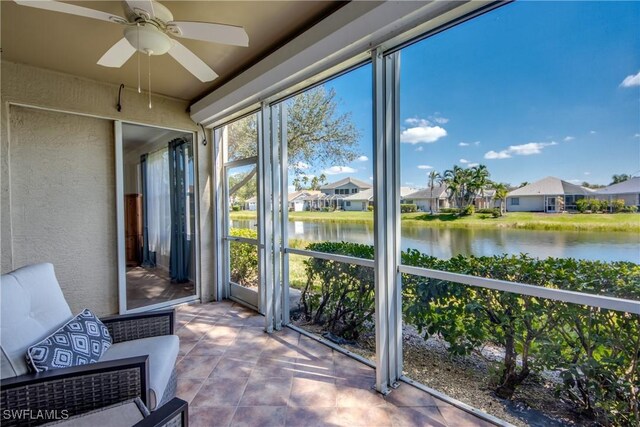 sunroom / solarium with ceiling fan, a water view, and a residential view