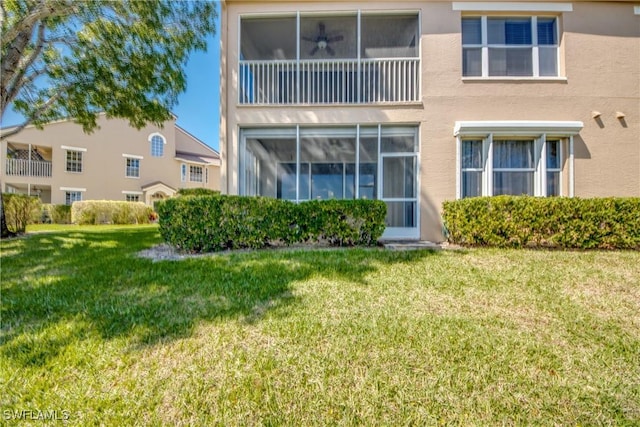 back of property with a yard and stucco siding