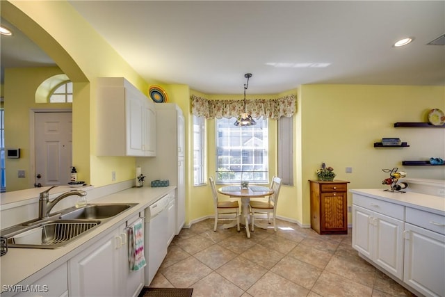 kitchen with arched walkways, white cabinets, white dishwasher, light countertops, and a sink