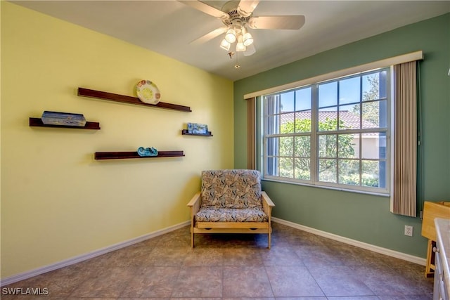 living area featuring baseboards, a ceiling fan, and tile patterned floors