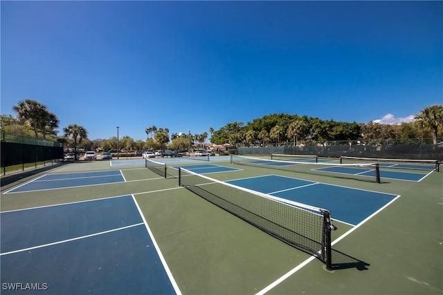 view of tennis court featuring community basketball court and fence