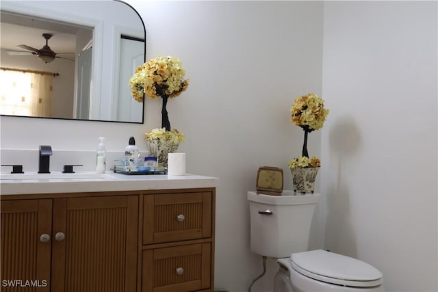 half bathroom with toilet, ceiling fan, and vanity