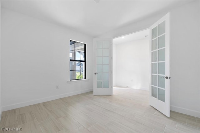 spare room featuring baseboards and french doors