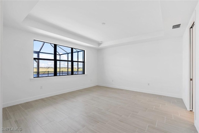 spare room featuring visible vents, a tray ceiling, and baseboards