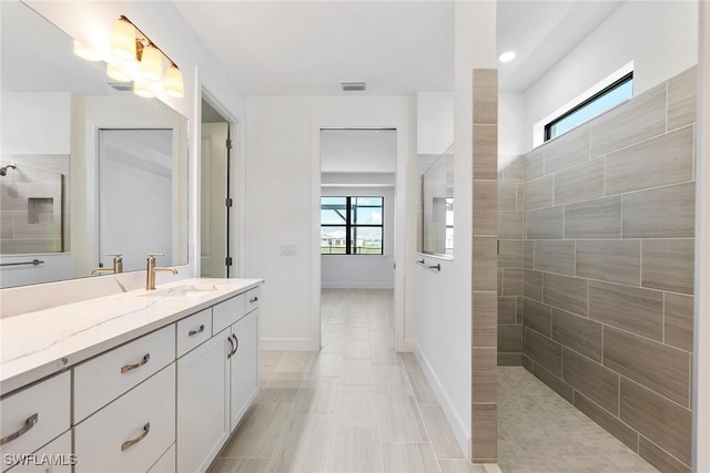 full bathroom featuring visible vents, walk in shower, vanity, and baseboards