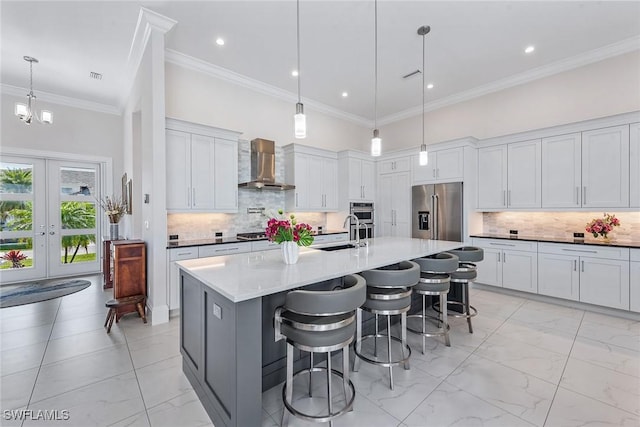 kitchen featuring a sink, a high ceiling, appliances with stainless steel finishes, and wall chimney exhaust hood