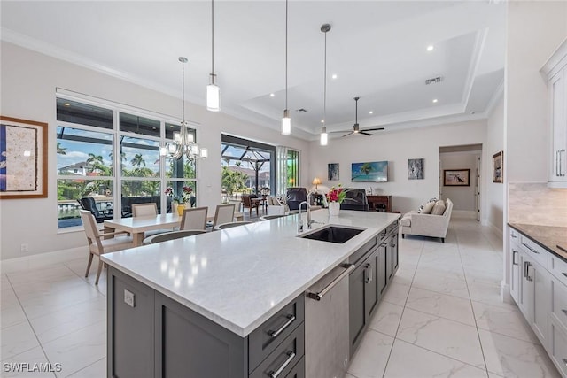 kitchen featuring marble finish floor, a sink, open floor plan, crown molding, and a raised ceiling