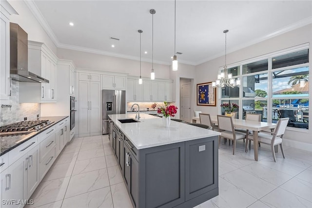 kitchen featuring appliances with stainless steel finishes, marble finish floor, white cabinetry, wall chimney exhaust hood, and a sink