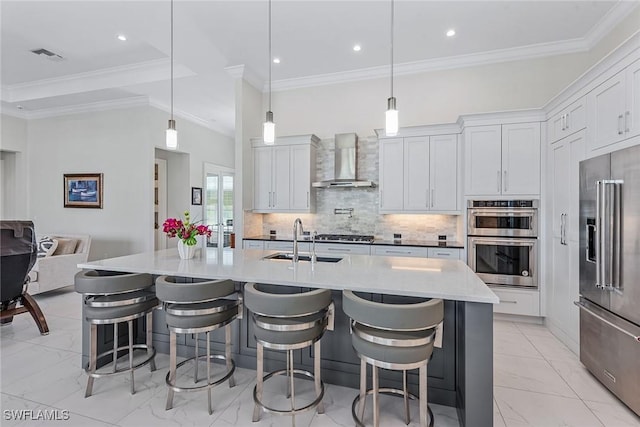 kitchen featuring visible vents, a sink, tasteful backsplash, stainless steel appliances, and wall chimney exhaust hood