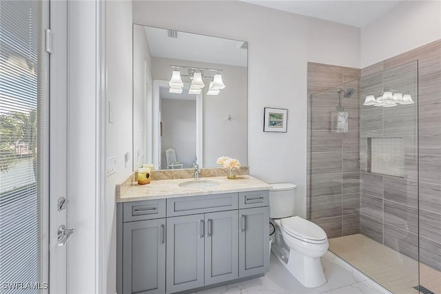 bathroom with vanity, toilet, marble finish floor, and a tile shower