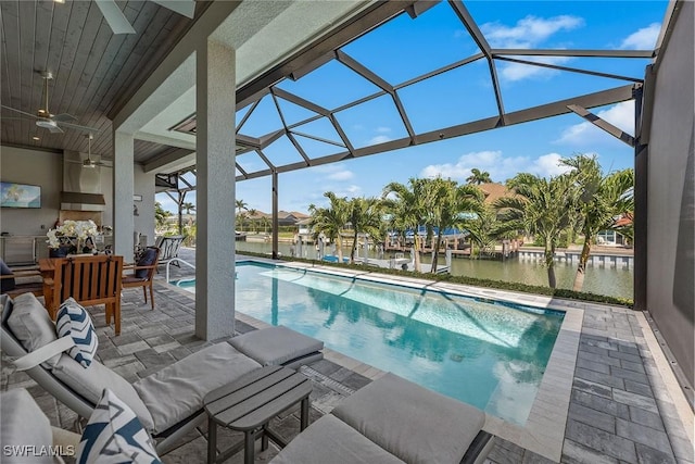 pool featuring a lanai, a ceiling fan, a patio, and a water view