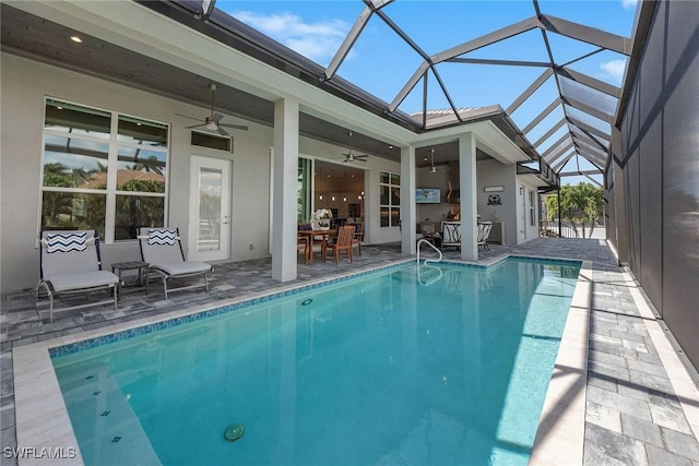 outdoor pool featuring glass enclosure, a ceiling fan, and a patio