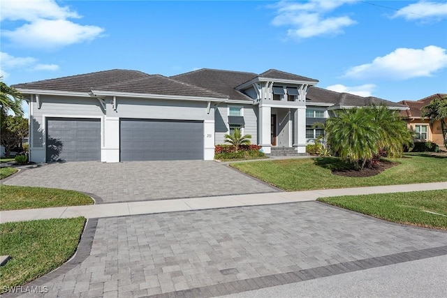 prairie-style house featuring a garage, decorative driveway, and a front yard