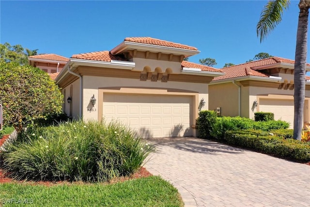 mediterranean / spanish home with a garage, a tiled roof, and stucco siding