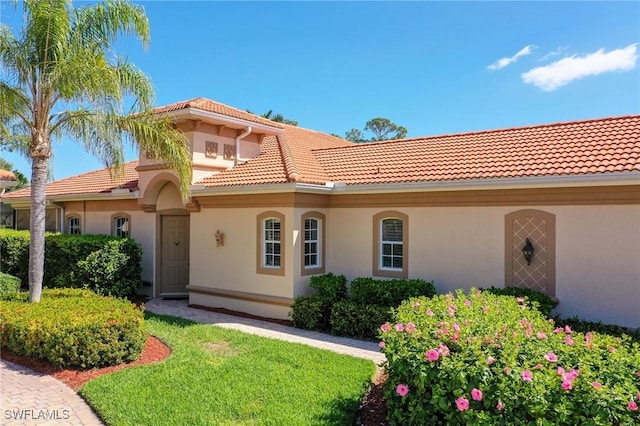 mediterranean / spanish home with a tiled roof and stucco siding