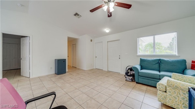 living area featuring ceiling fan, visible vents, light tile patterned flooring, and vaulted ceiling