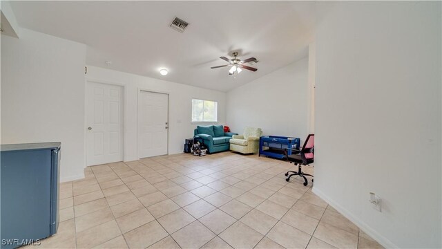 living area featuring light tile patterned floors, baseboards, visible vents, ceiling fan, and vaulted ceiling