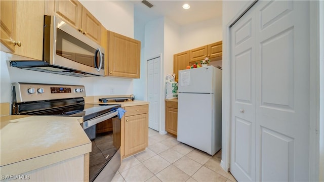 kitchen with visible vents, light brown cabinets, appliances with stainless steel finishes, light tile patterned flooring, and light countertops