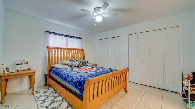 bedroom with light tile patterned floors, two closets, and ceiling fan