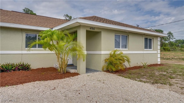 view of side of home featuring stucco siding and roof with shingles