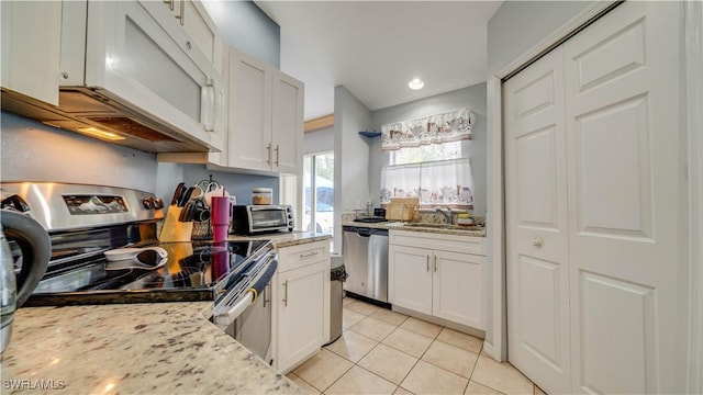 kitchen featuring light tile patterned flooring, white cabinets, stainless steel appliances, and light stone countertops