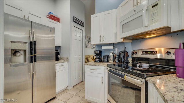 kitchen with appliances with stainless steel finishes, light tile patterned flooring, and white cabinetry