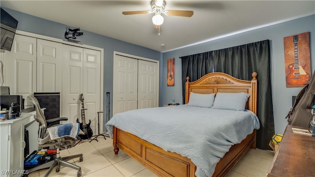 bedroom with light tile patterned floors, multiple closets, and ceiling fan