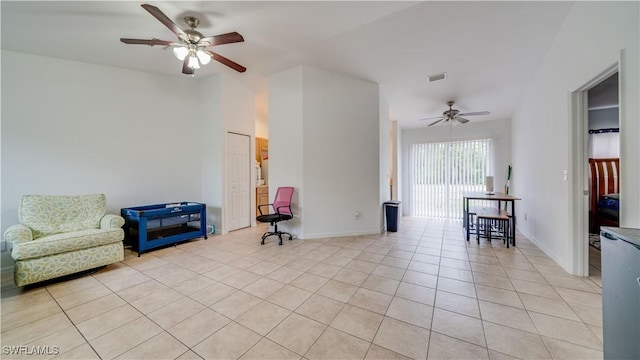 living area featuring light tile patterned floors, visible vents, ceiling fan, and baseboards