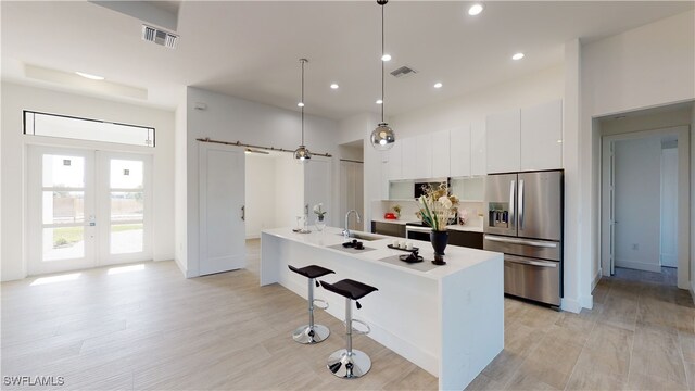 1523 NW 34th Ave, Cape Coral, FL 33993 - kitchen featuring stainless steel fridge, modern cabinets, white cabinets, a breakfast bar area, and french doors