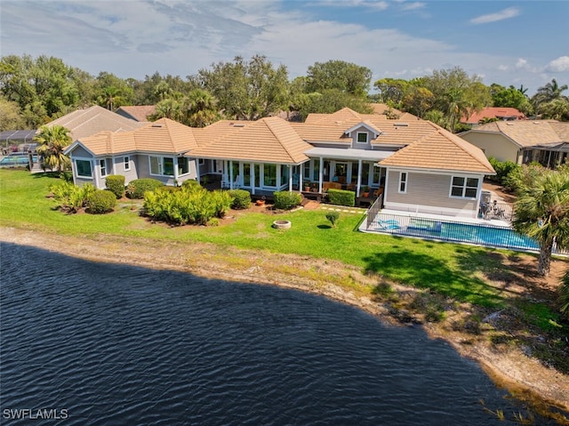 rear view of house with a fenced in pool, a tile roof, a yard, a water view, and fence