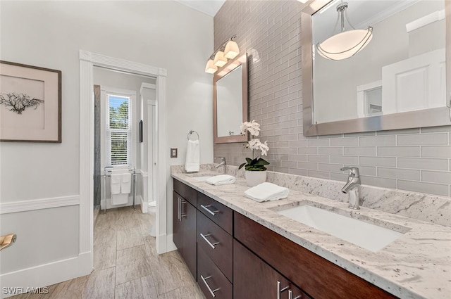 bathroom featuring tasteful backsplash, a sink, toilet, and double vanity