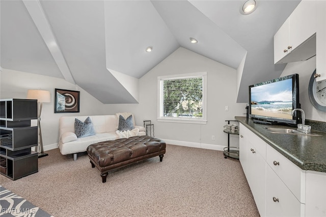 bedroom featuring lofted ceiling, baseboards, a sink, and light colored carpet