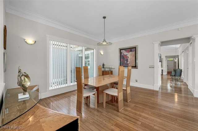 dining space featuring light wood-type flooring, crown molding, baseboards, and decorative columns