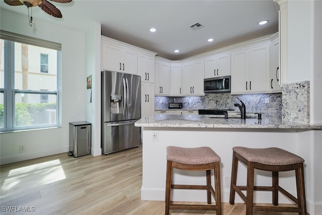 kitchen with stainless steel appliances, tasteful backsplash, visible vents, white cabinetry, and a peninsula