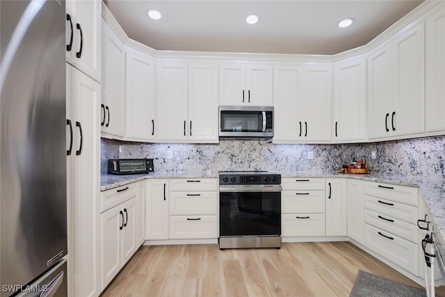 kitchen featuring stainless steel appliances, white cabinetry, light wood finished floors, and light stone countertops