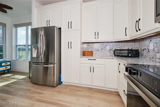 kitchen featuring range, stainless steel fridge with ice dispenser, light stone countertops, light wood-type flooring, and white cabinetry