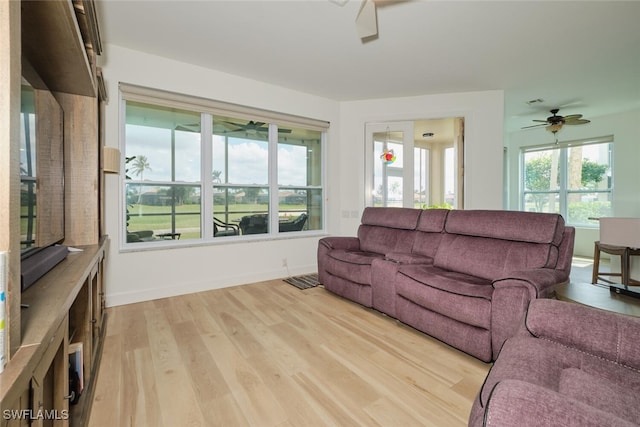 living room with light wood-style floors, ceiling fan, and baseboards