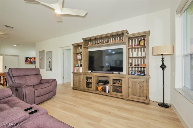 living area with baseboards, wood finished floors, visible vents, and a ceiling fan