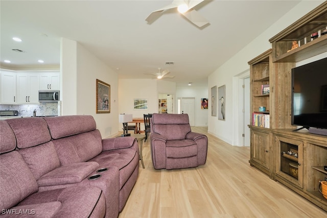 living room featuring light wood-type flooring, a ceiling fan, and recessed lighting