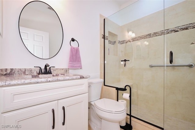 bathroom with toilet, a stall shower, and vanity