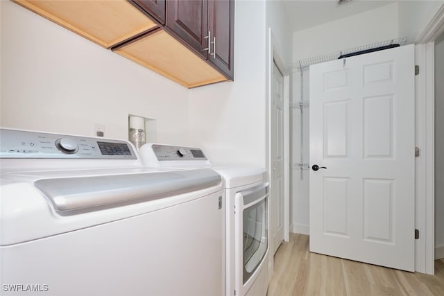 laundry room with cabinet space, light wood-style flooring, and washing machine and clothes dryer