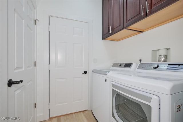 laundry area featuring light wood-style flooring, washing machine and dryer, and cabinet space