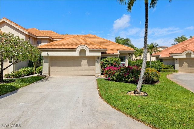 mediterranean / spanish-style home with a garage, a tile roof, concrete driveway, stucco siding, and a front lawn