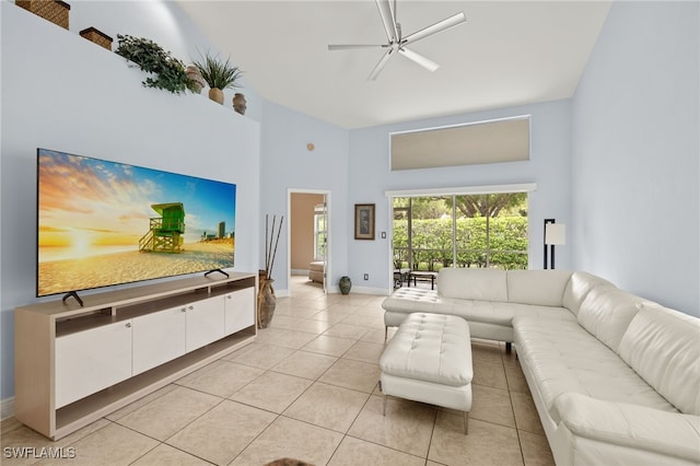 living area with light tile patterned floors, a towering ceiling, a ceiling fan, and baseboards