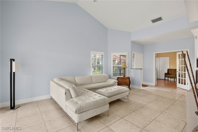 living room featuring french doors, light tile patterned floors, visible vents, high vaulted ceiling, and baseboards