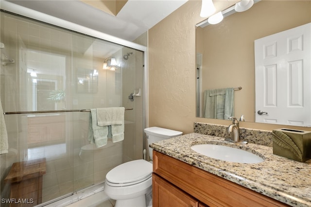 full bathroom featuring toilet, a stall shower, vanity, and a textured wall