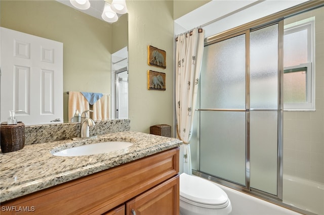 full bathroom featuring toilet, shower / bath combination with glass door, and vanity