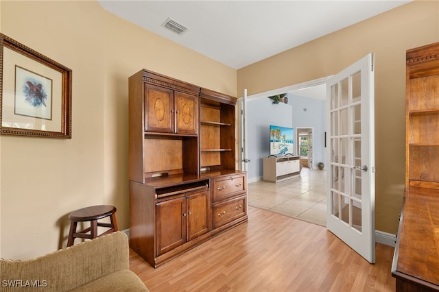 home office featuring baseboards, visible vents, french doors, and light wood finished floors